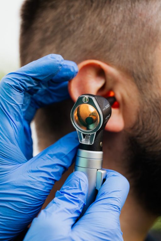 Man gets an ear exam from doctor with otoscope.